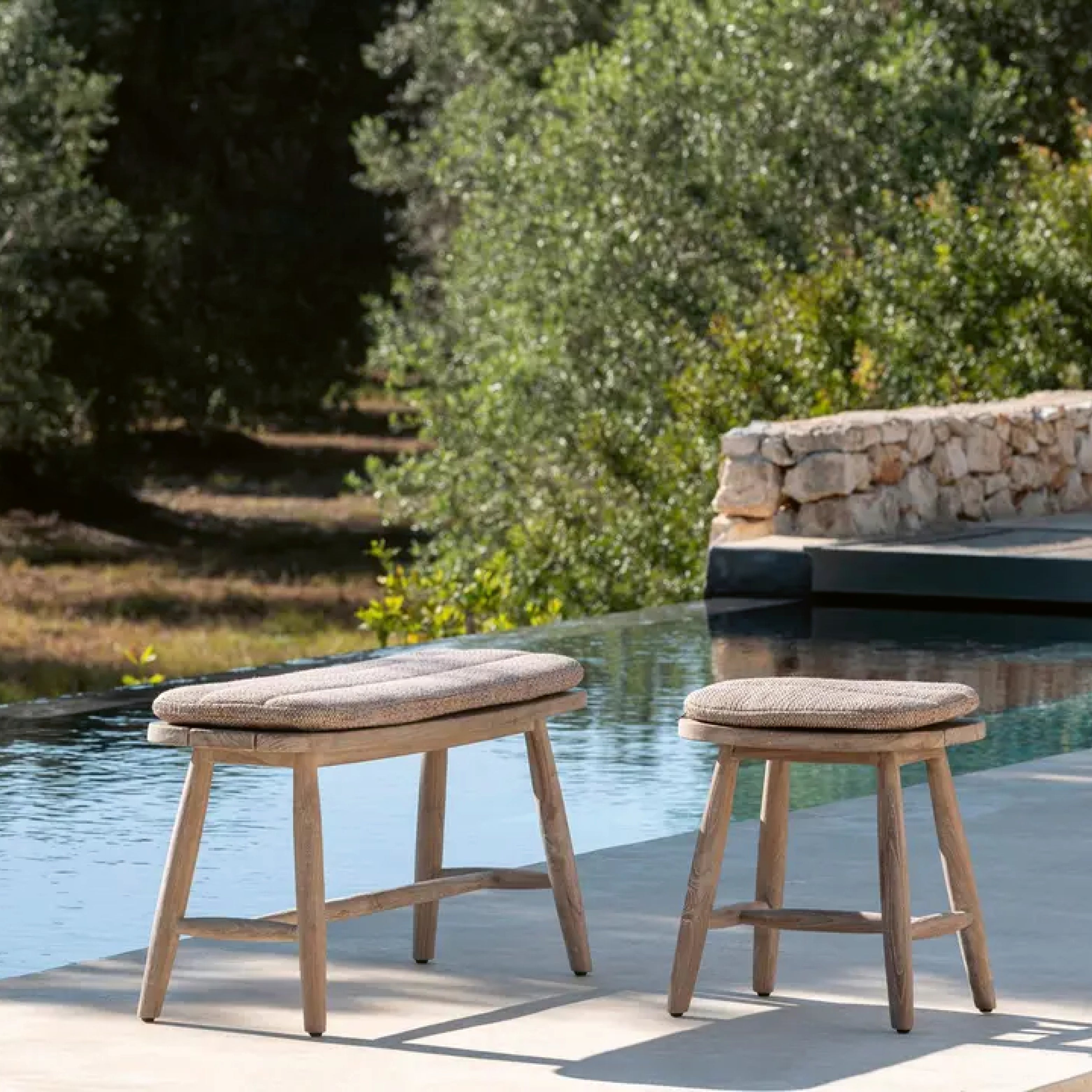 Teakholz-Gartenhocker mit Polster auf Poolterrasse im mediterranen Garten