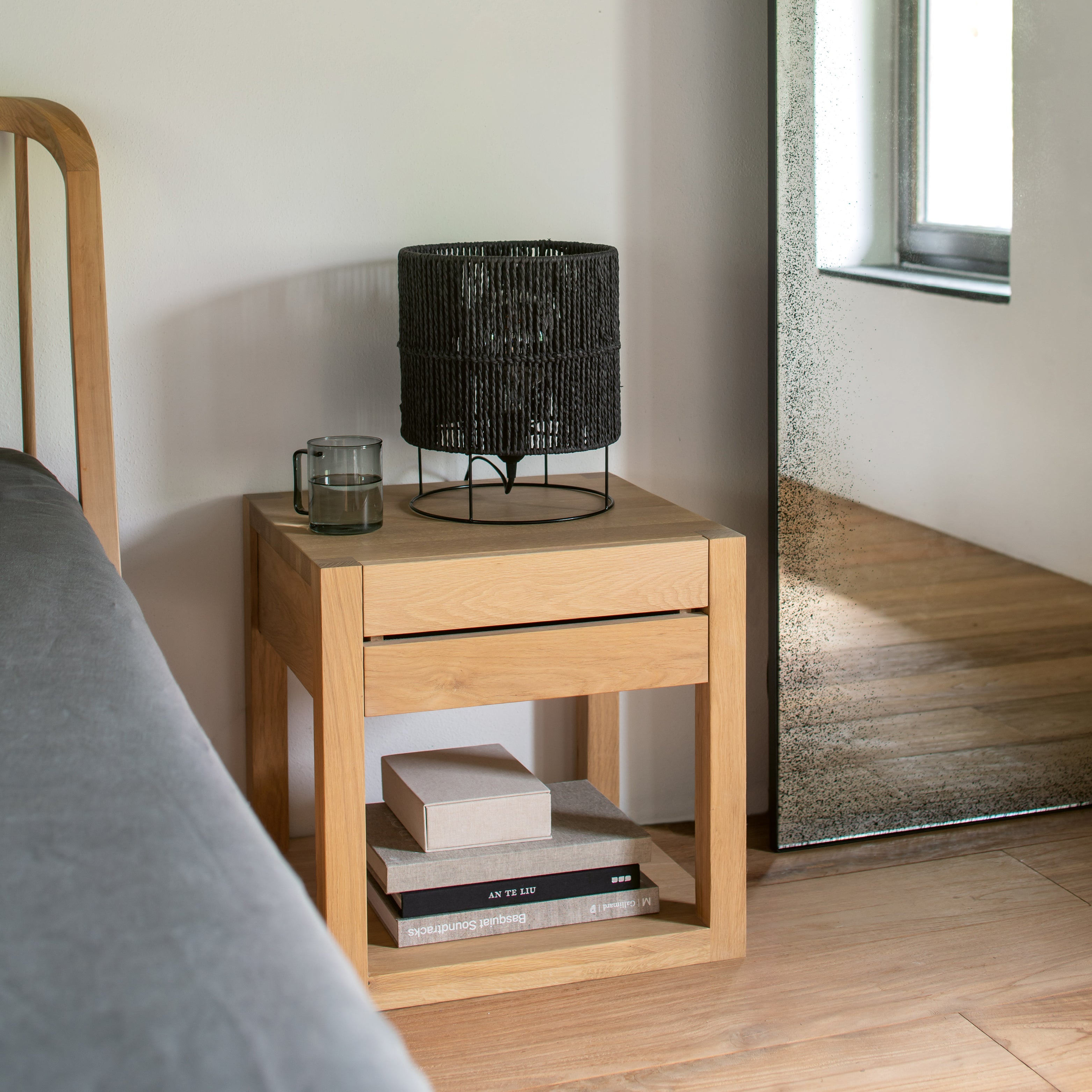 Schlafzimmer mit Massivholzbett, Nachttisch und weichen Textilien in heller, entspannter Atmosphäre