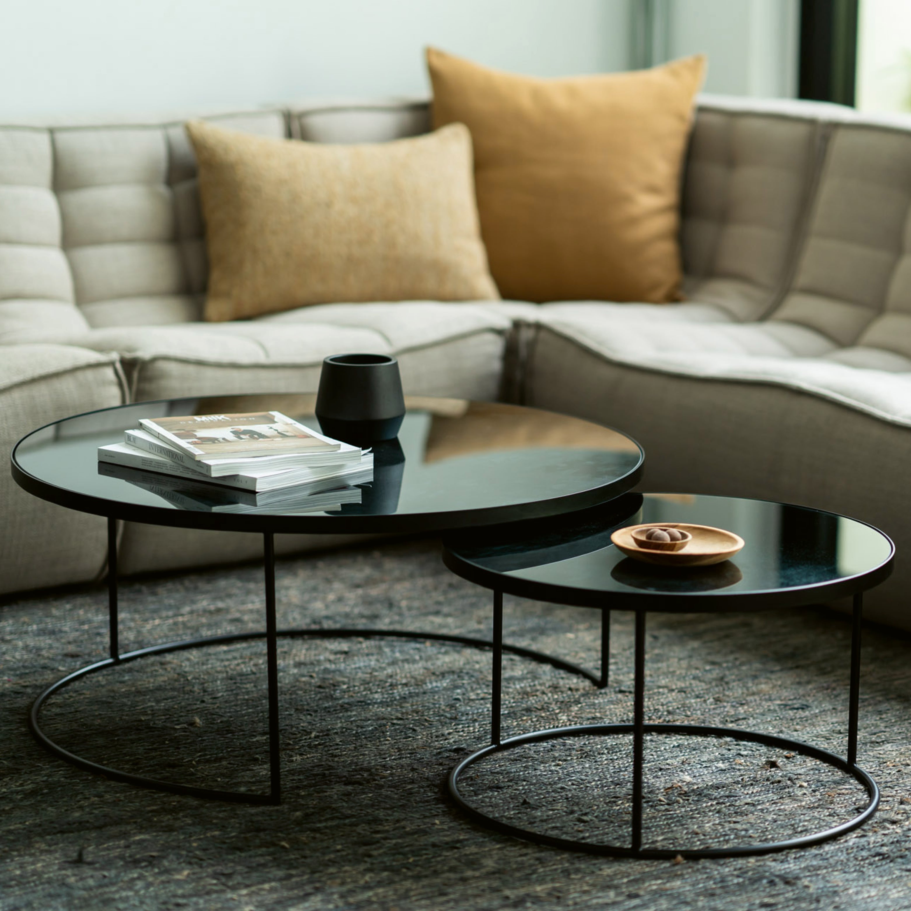 Zweiteiliges Couchtisch-Set mit schwarzer Glasplatte und Metallgestell – modernes Wohnzimmer mit Sofa in Naturtönen