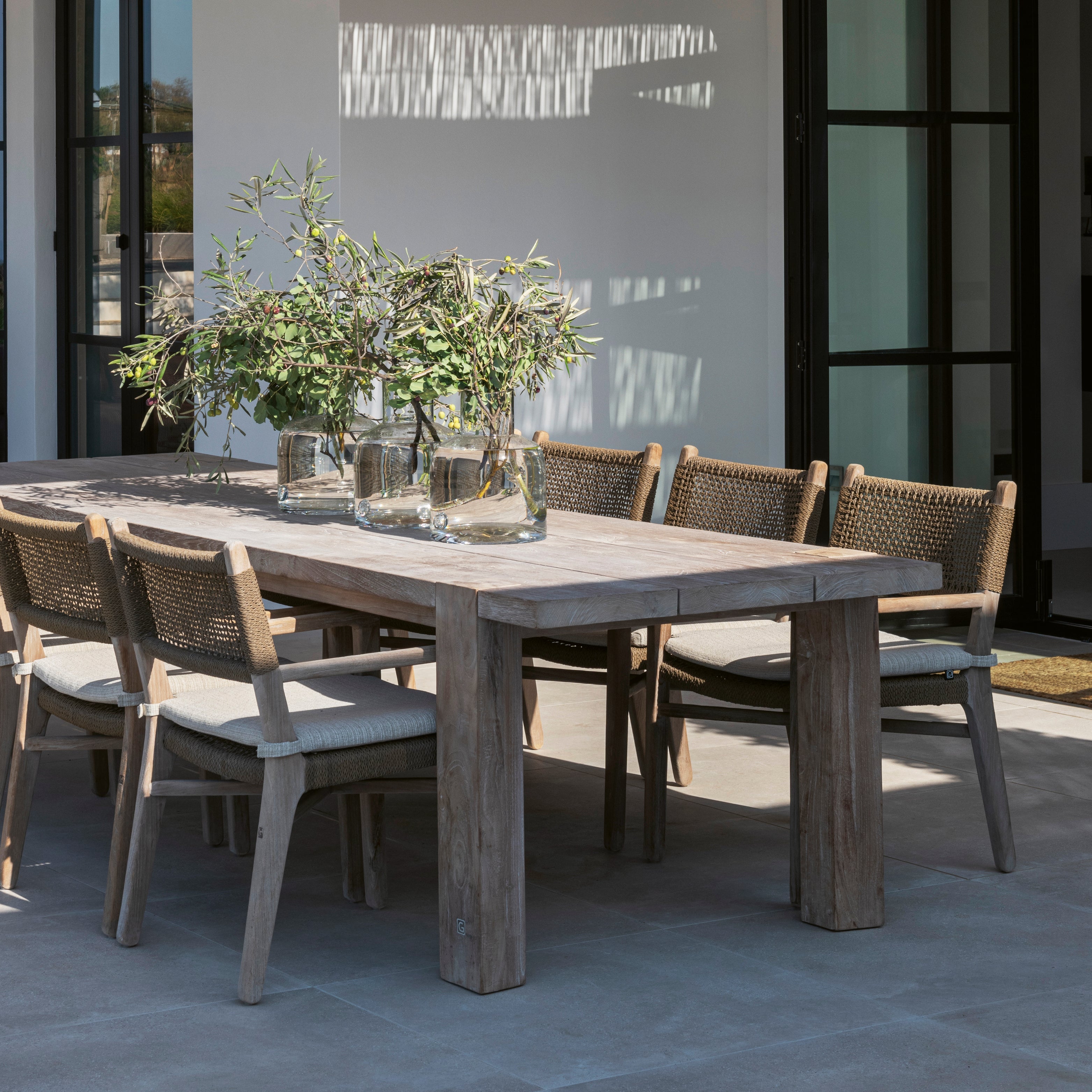 Massiver Gommaire Gartentisch aus recyceltem Teakholz mit sechs geflochtenen Outdoor-Stühlen – nachhaltiges Design für stilvolle Essterrassen.