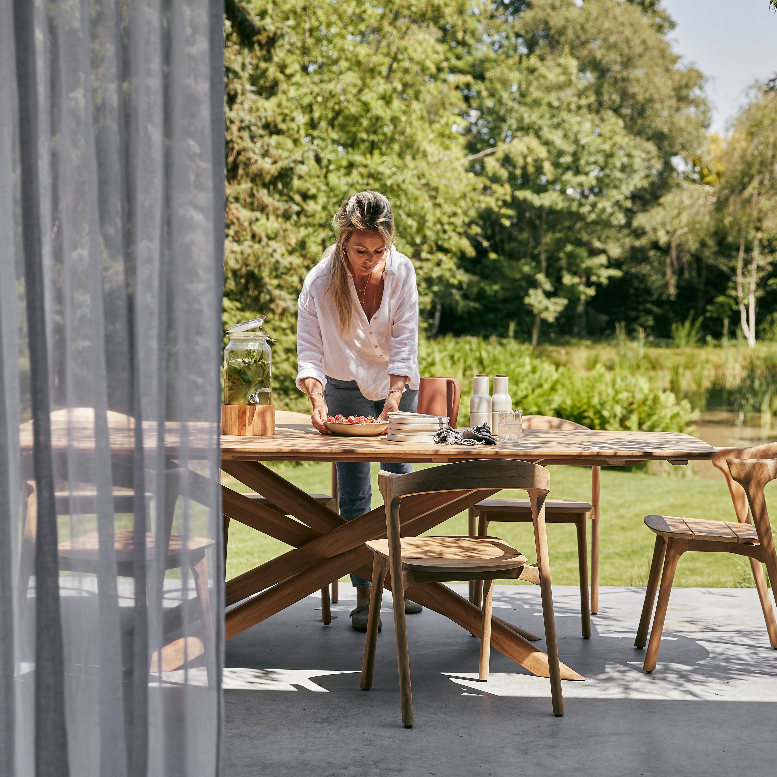 Gartenmöbel von Ethnicraft aus Teakholz – moderner Esstisch mit Stühlen auf Terrasse im Grünen.