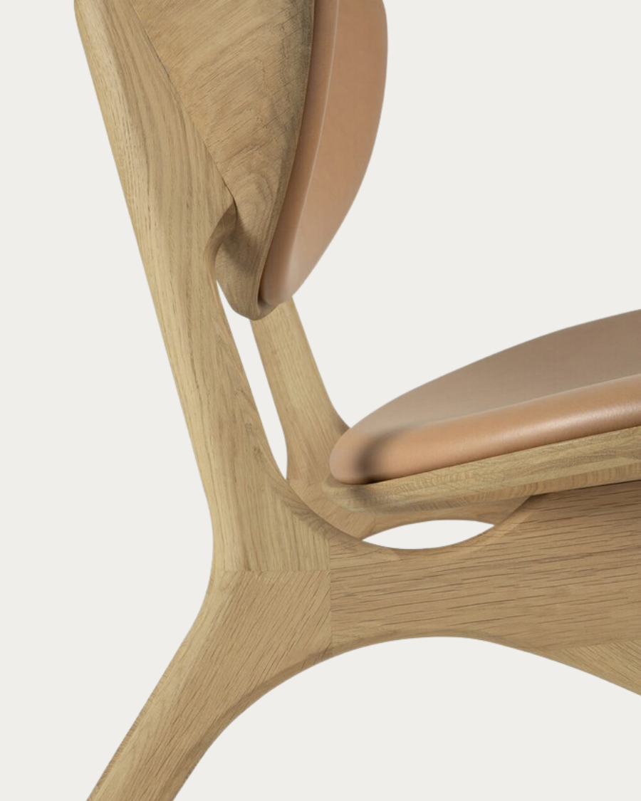 Detailaufnahme der geschwungenen Rückenlehne des EYE Sessels mit einer Leder in Sienna Polsterung