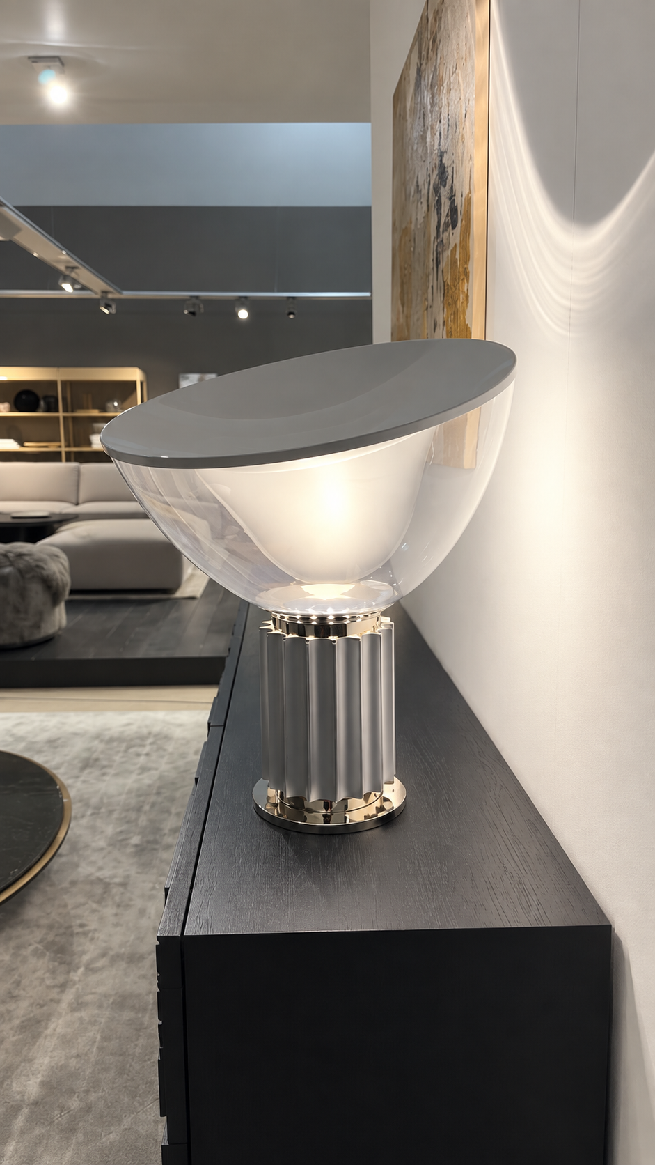 Lampe de table Flos TACCIA en aluminium et argent posée sur une commode