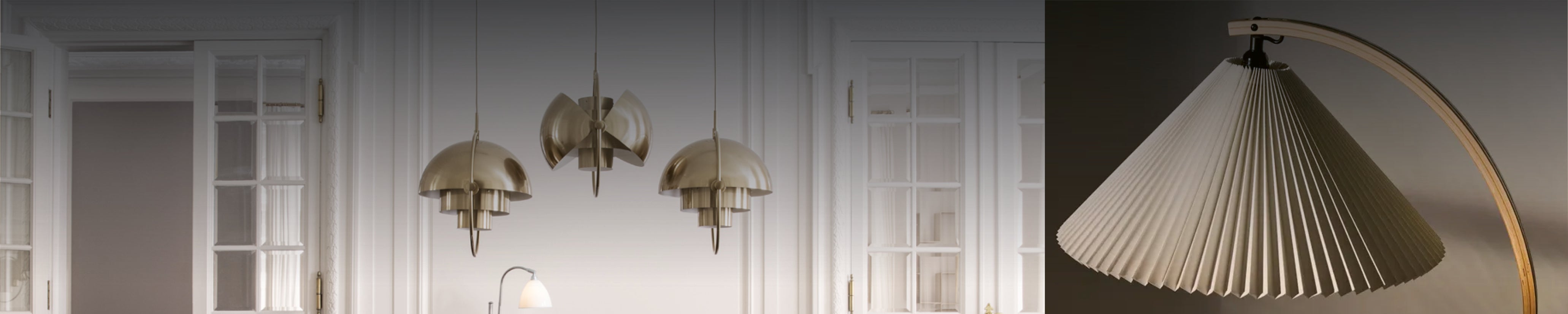 Eleganter Essbereich mit drei goldenen Pendelleuchten von Gubi und geschwungenem Holzarm im minimalistischen Stil.