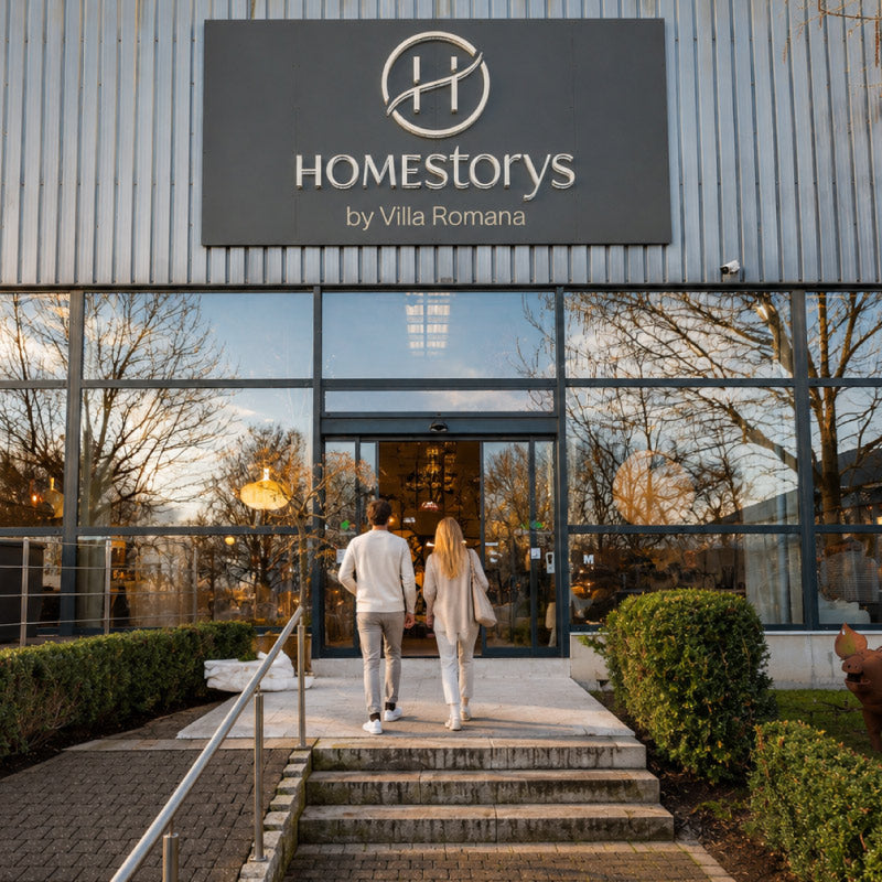 Ein Paar betritt den Homestorys-Showroom in Eupen. Über dem Eingang ist das vollständige Homestorys-Logo zu sehen.