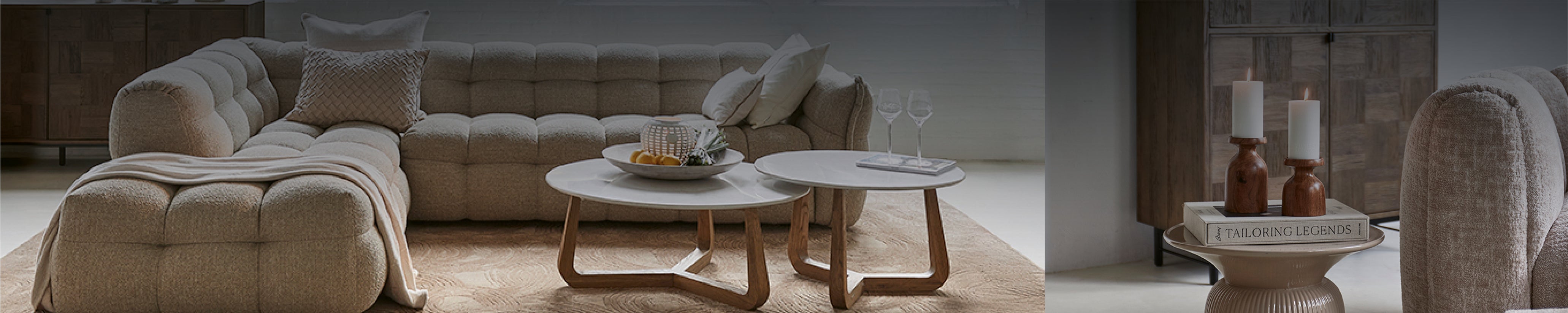 Modulares Sofa in Bouclé mit Holzfüßen, zwei runde Loungetische und Kerzendeko – stilvolles Riviera Maison Wohnzimmer.