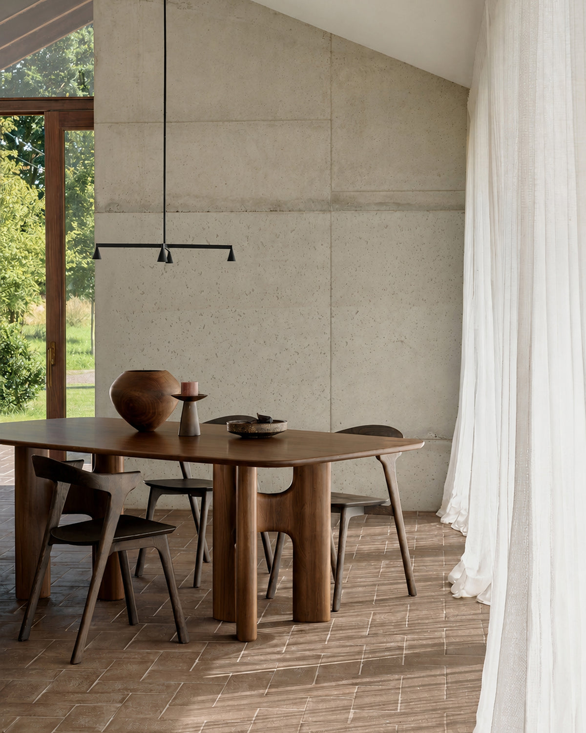 Ethnicraft FLOW dining table made of solid teak in Wild Brown, paired with modern dining chairs in a bright dining area.