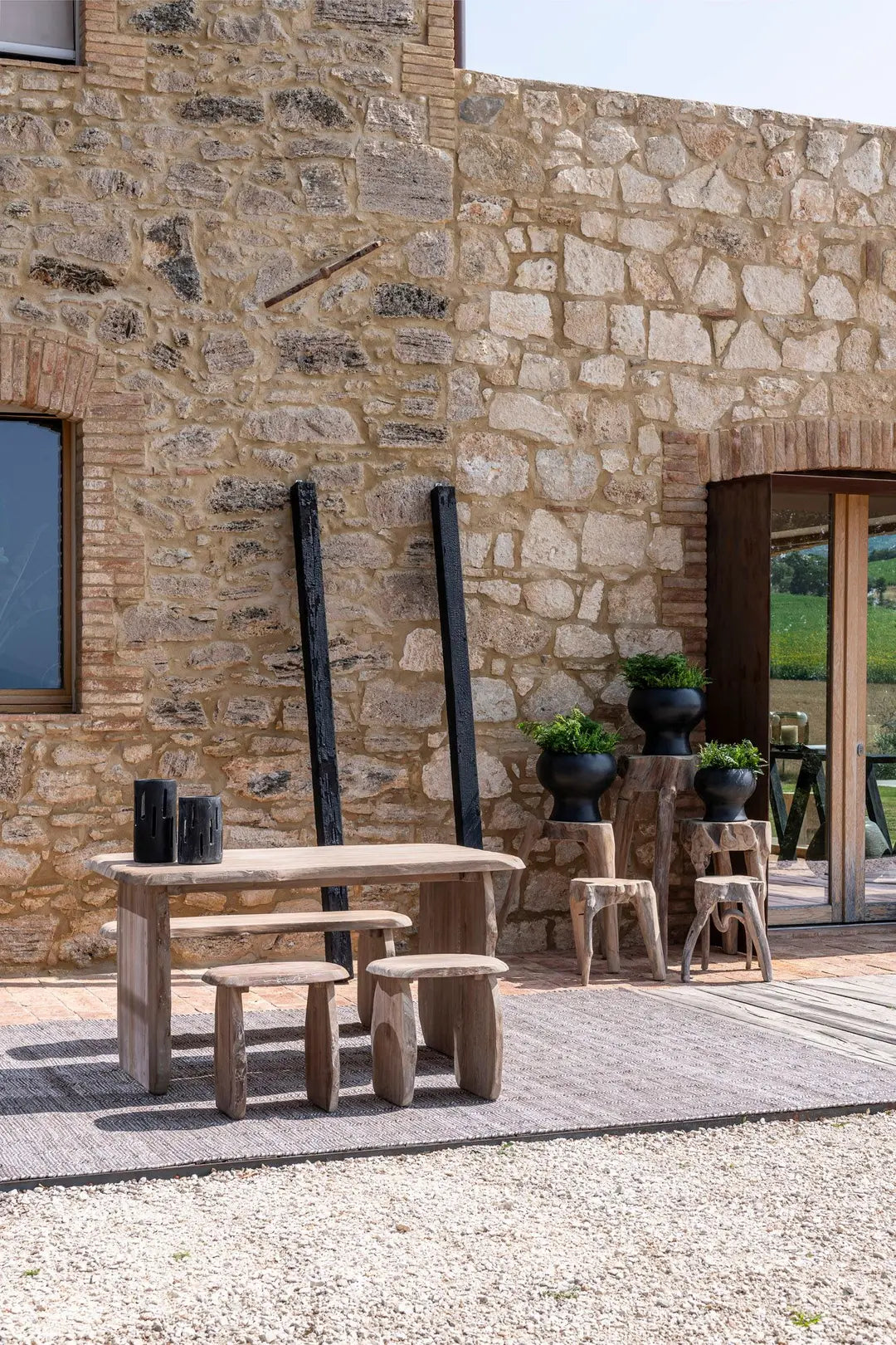 Pebble teak stool from Gommaire in a garden setting - versatile as a Side table or seat