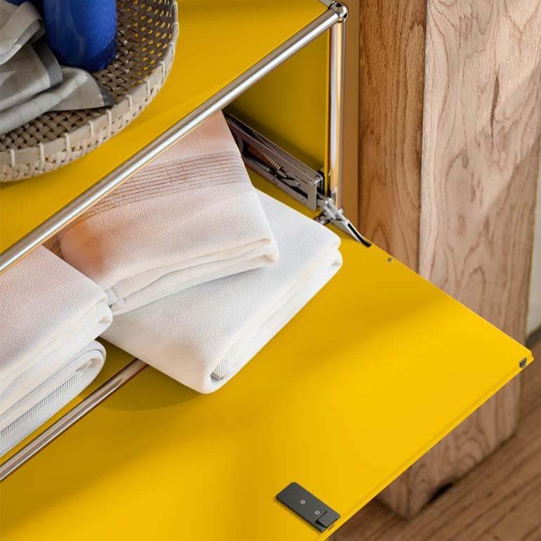 USM Kommode G1 in Goldgelb mit geöffnetem Fach – praktische Beispieleinrichtung mit sichtbarem Stauraum für Ordner, Deko oder Alltagsgegenstände im modernen Wohnbereich