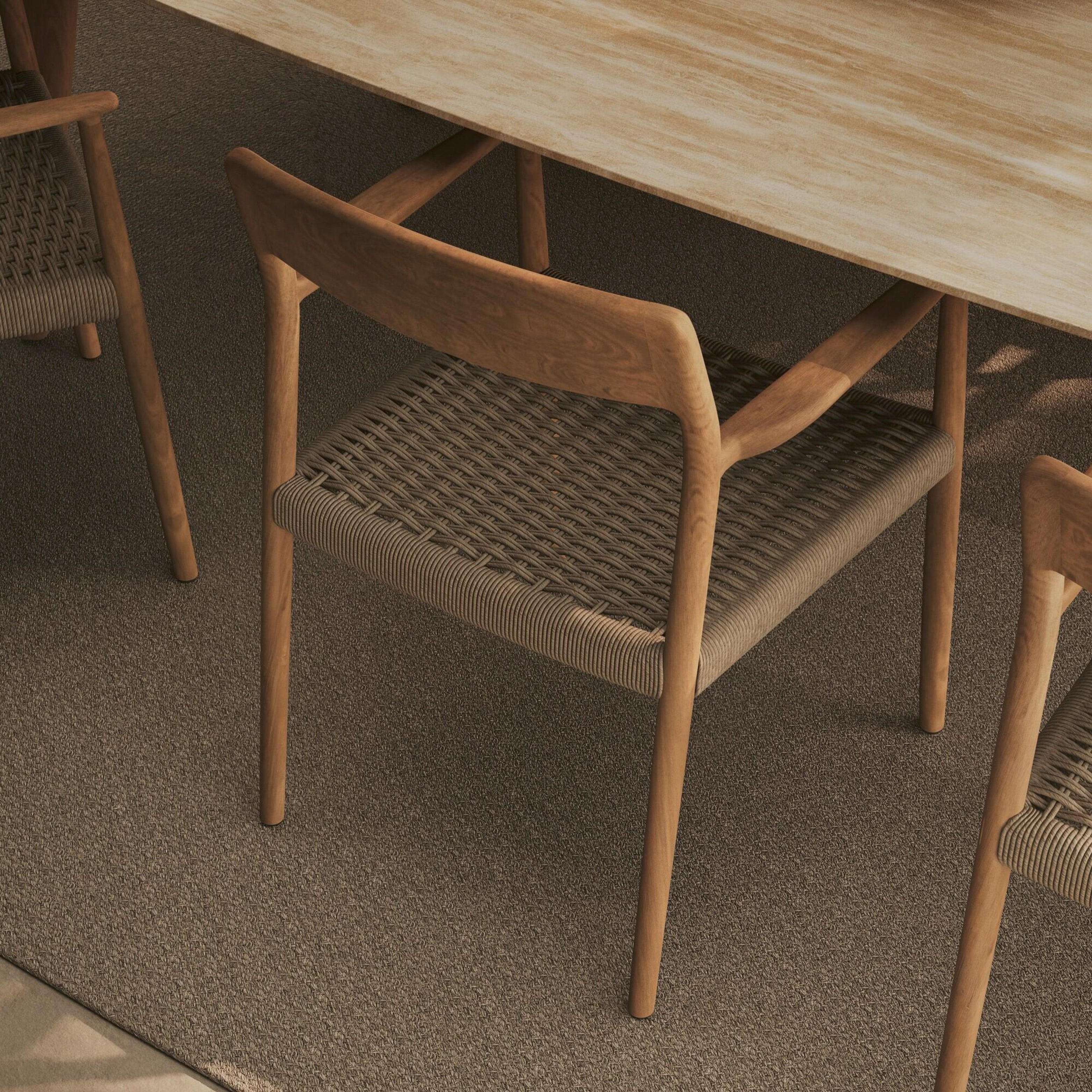 Detailansicht eines Manutti Gartenstuhls mit Holzrahmen und geflochtener Sitzfläche auf Outdoor-Teppich