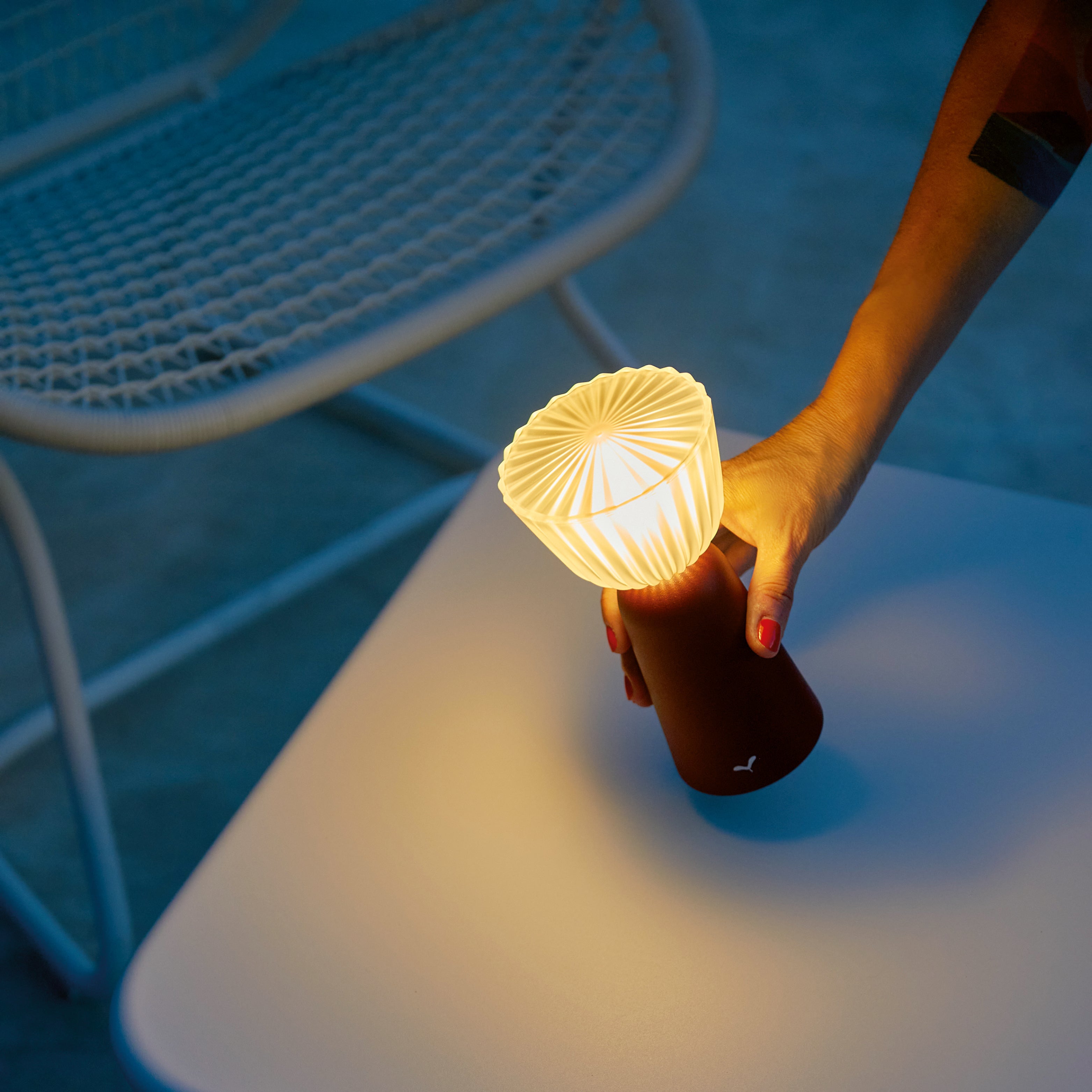 Kabellose Outdoor Tischlampe mit LED-Licht auf rundem Beistelltisch aus Metall neben Gartenstuhl