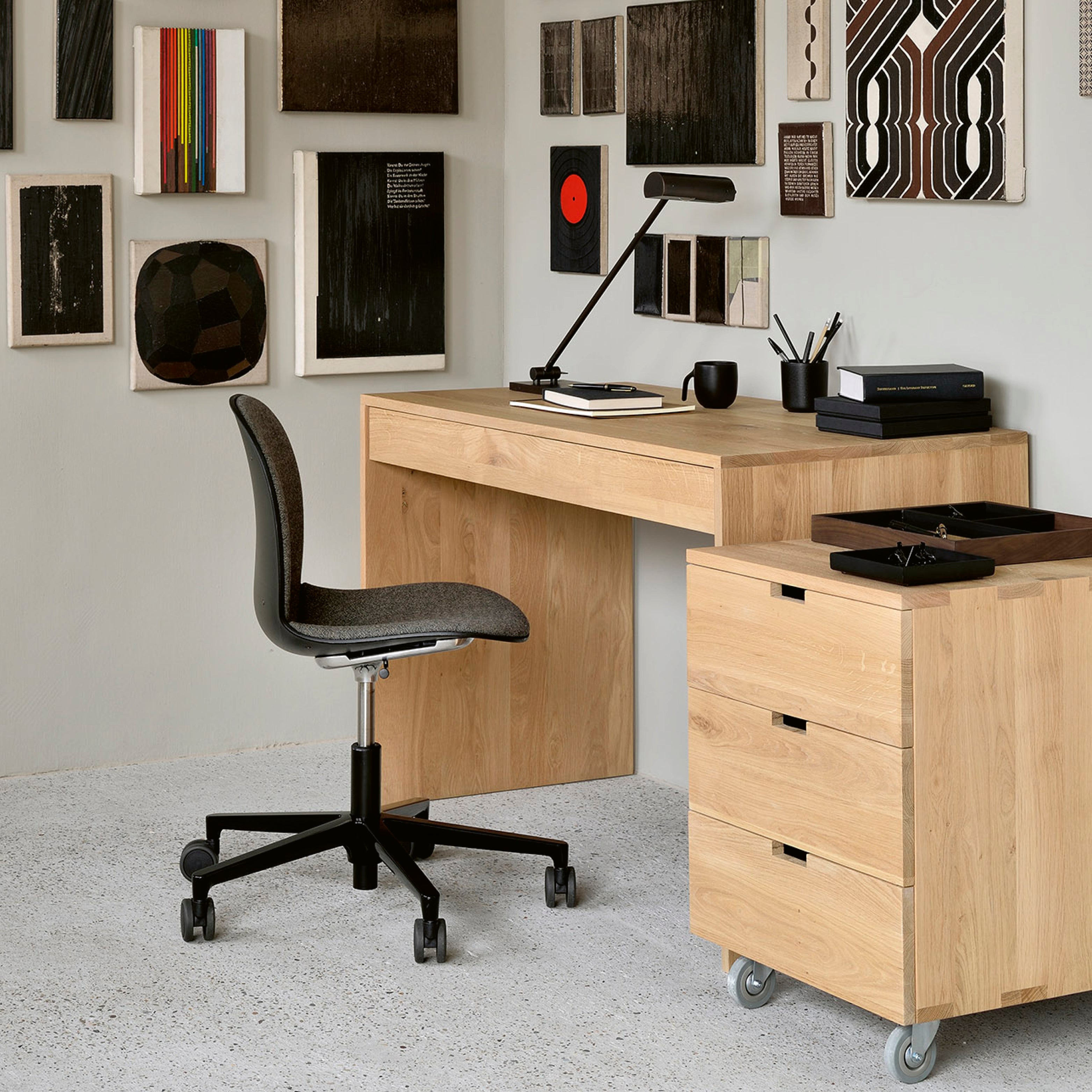 Minimalistischer Design-Schreibtisch aus heller Eiche mit Rollcontainer und ergonomischem Bürostuhl in modernem Homeoffice.