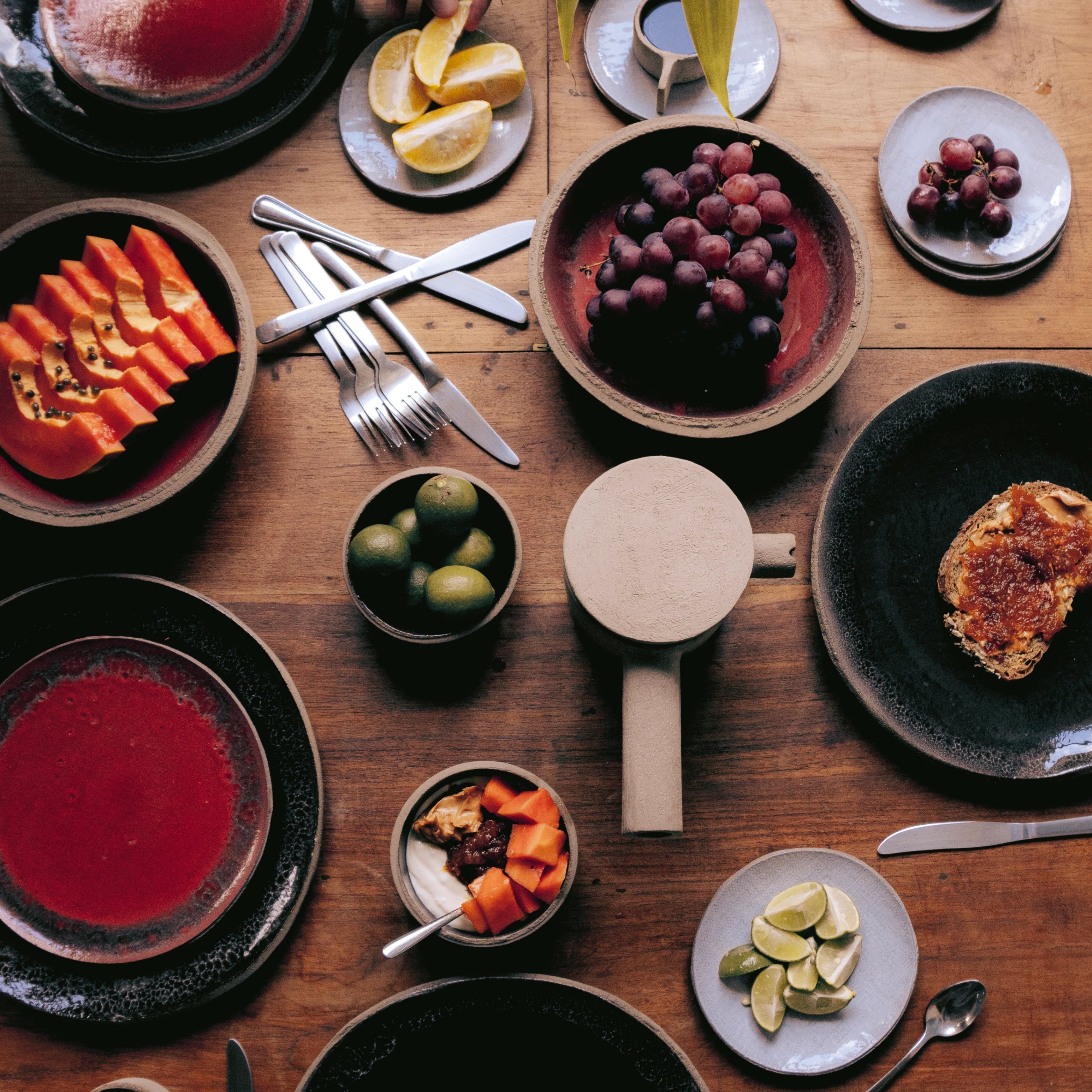 Serax PURE Teller und Schalen in kräftigen Farben, gedeckter Tisch mit frischen Früchten und stilvollen Accessoires in moderner Food-Präsentation.