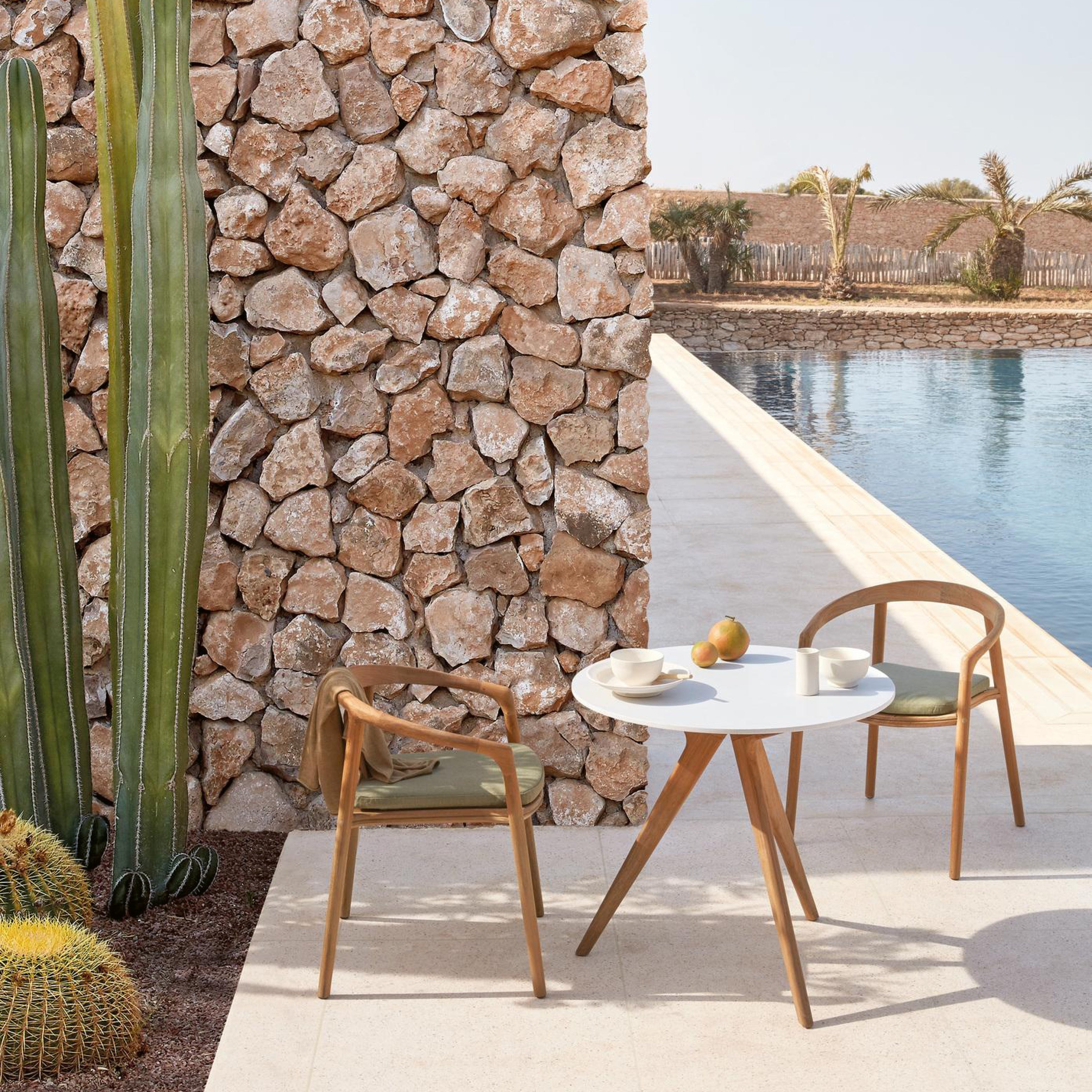 Outdoor-Gartentisch mit runder Tischplatte aus hellem Material und Holzgestell mit zwei Stühlen auf Terrasse