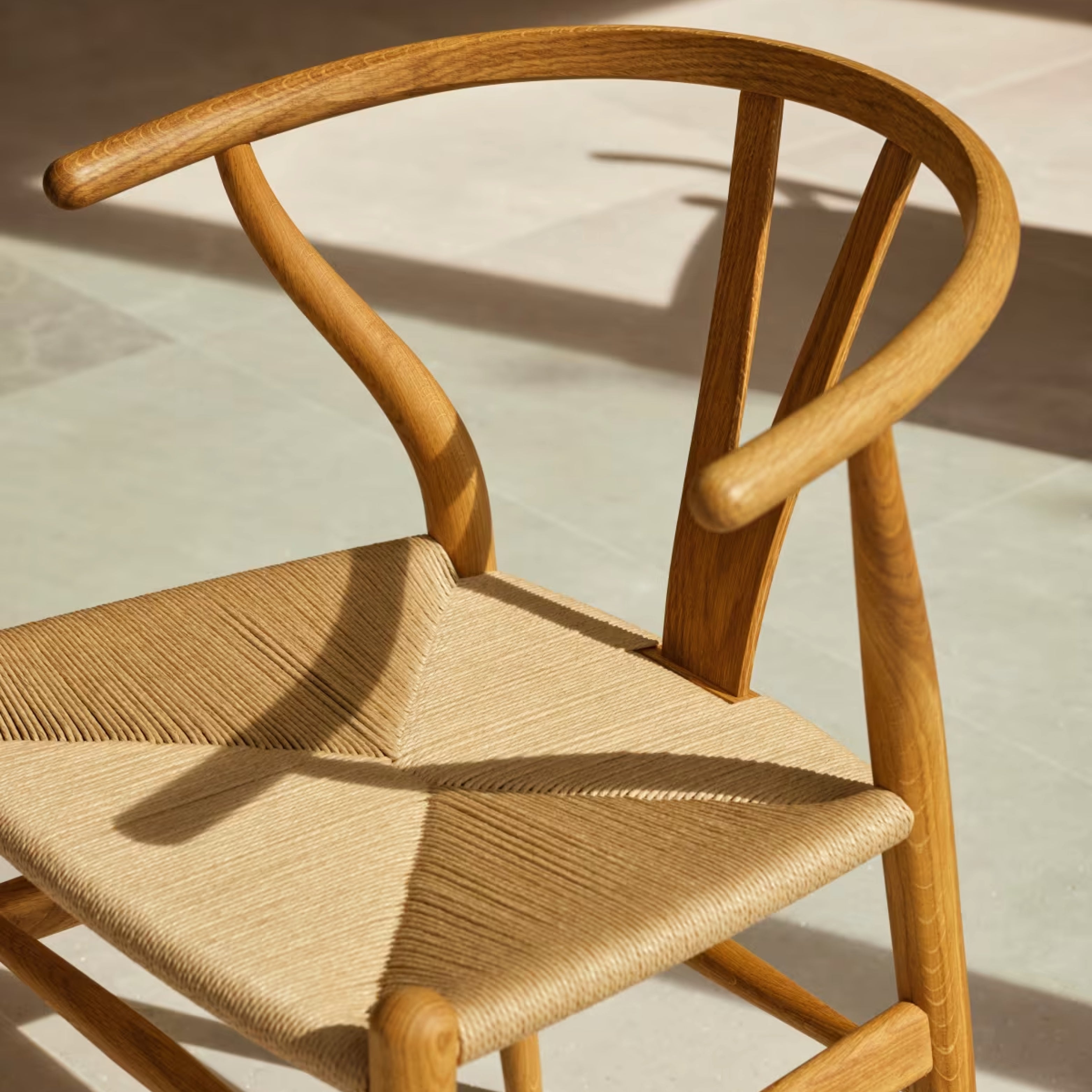 Detailansicht des Wishbone Stuhls von Carl Hansen & Søn – Massivholzgestell in Eiche mit Y-förmiger Rückenlehne und geflochtenem Sitz aus Naturkordel.