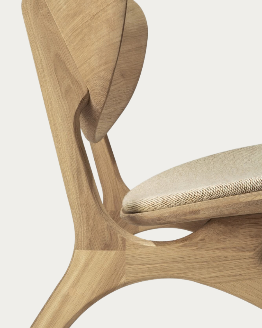 Detailaufnahme der geschwungenen Rückenlehne des EYE Sessels mit einer Polsterung in Off White,