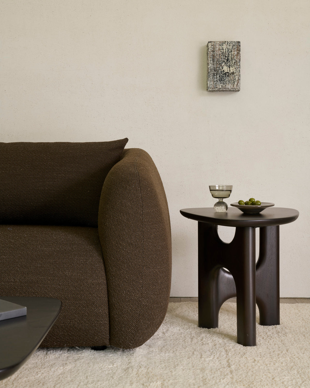 Table d'appoint d'Ethnicraft FLOW en acajou, couleur Rose Brown, à côté d'un canapé moderne dans le salon.