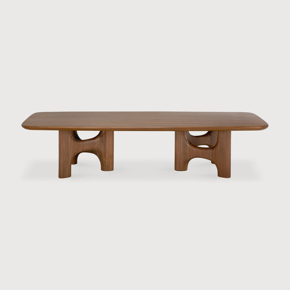 Table basse FLOW en bois massif, avec un plateau arrondi et des pieds au design marquant, vue de face.