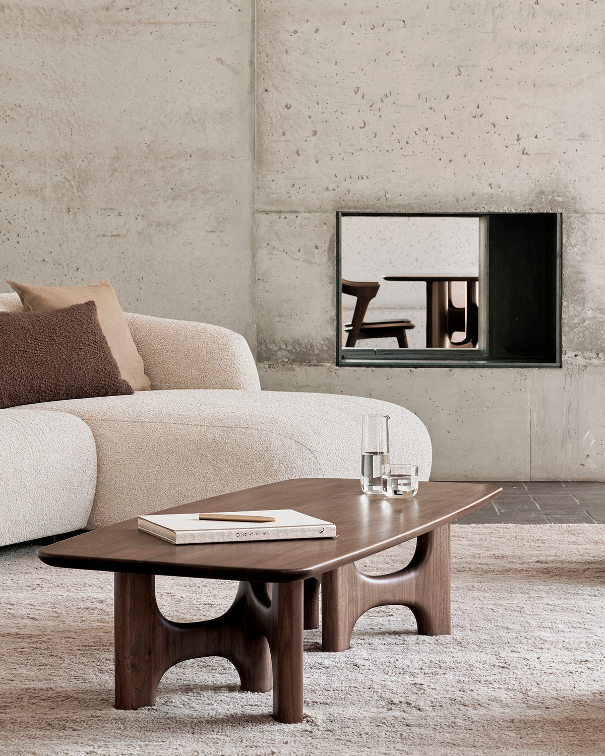 Table basse d'Ethnicraft FLOW en teck « Wild Brown », aux lignes fluides, dans un salon moderne aux matériaux naturels.