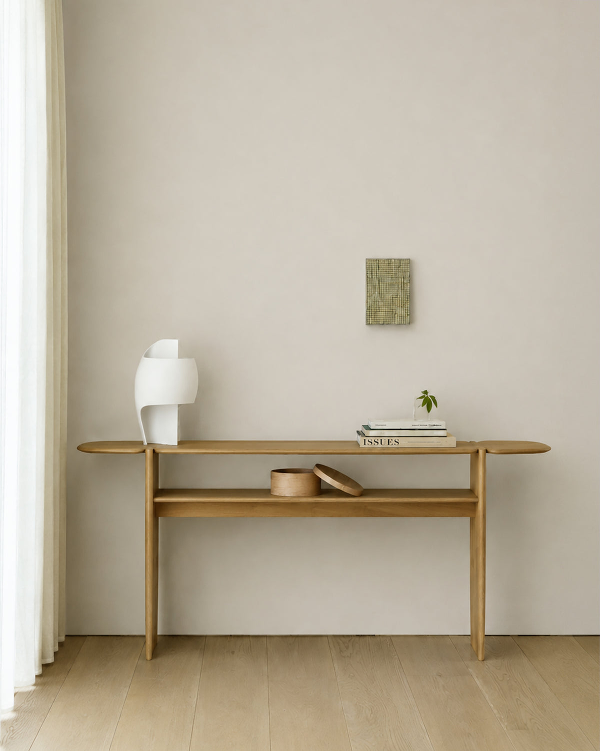 Console PI d'Ethnicraft 160 x 75 cm en chêne, agrémentée d'objets décoratifs, dans une entrée lumineuse.