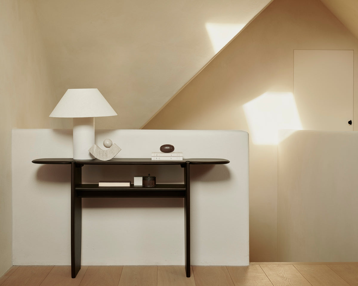 Console PI d'Ethnicraft 130 x 75 cm en acajou foncé, agrémentée d'objets décoratifs, dans une entrée lumineuse.