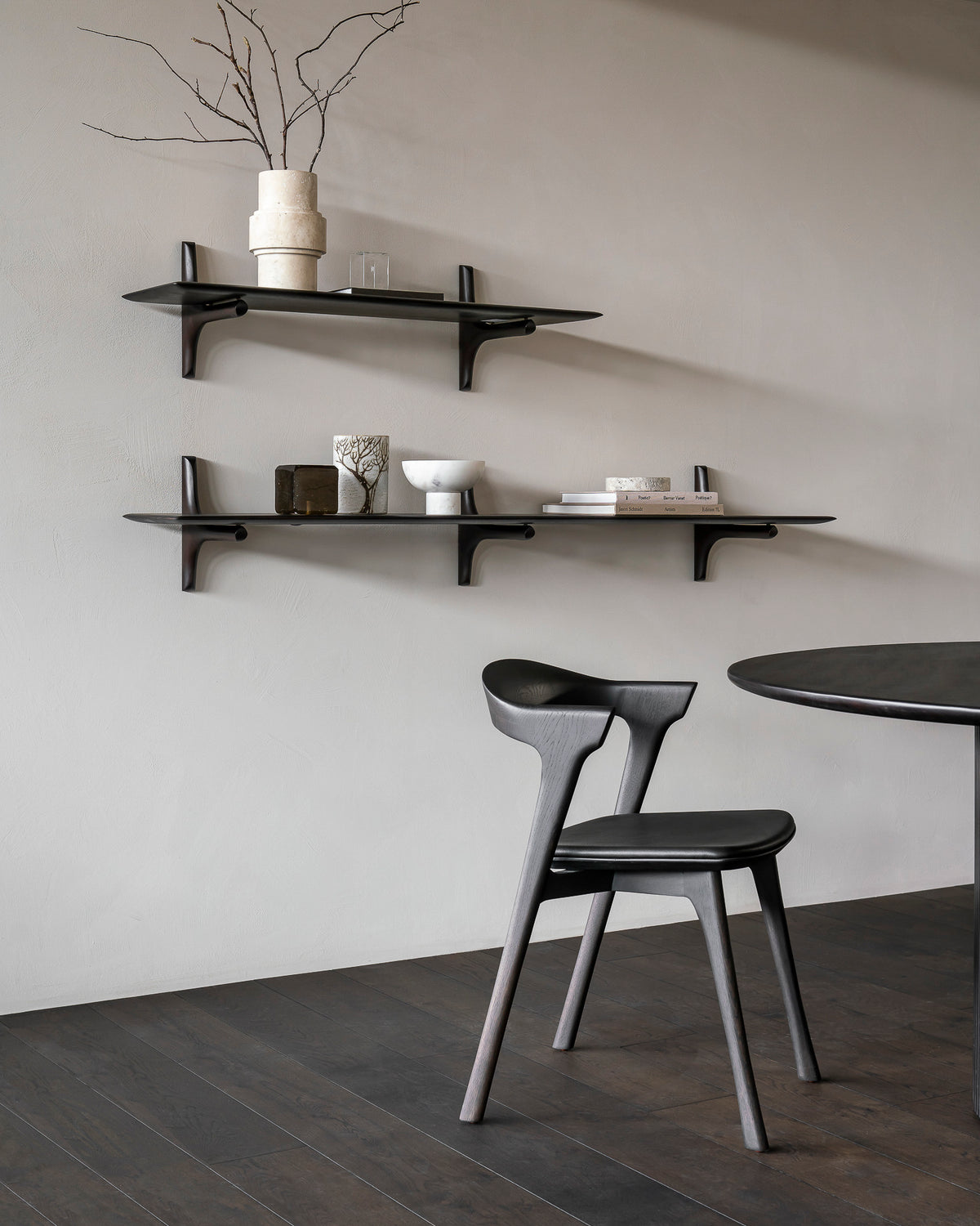 Étagère murale d'Ethnicraft PI en acajou massif, couleur marron foncé, avec des livres et des objets décoratifs, fixée au mur d'un salon.