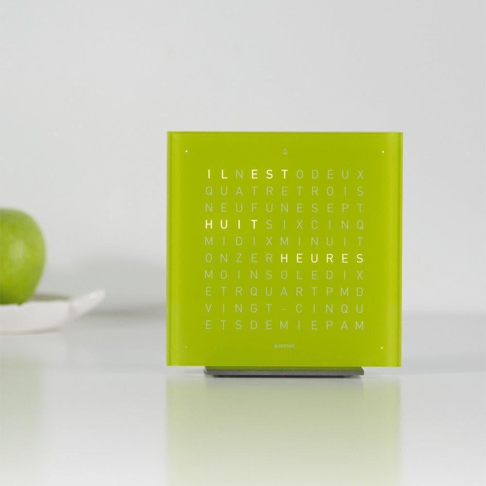 QLOCKTWO EARTH 13.5 Pure Lime Juice – leuchtend grüne Design-Tischuhr mit typografischer Zeitanzeige, stilvoll platziert auf einem Tisch in modernem Interior