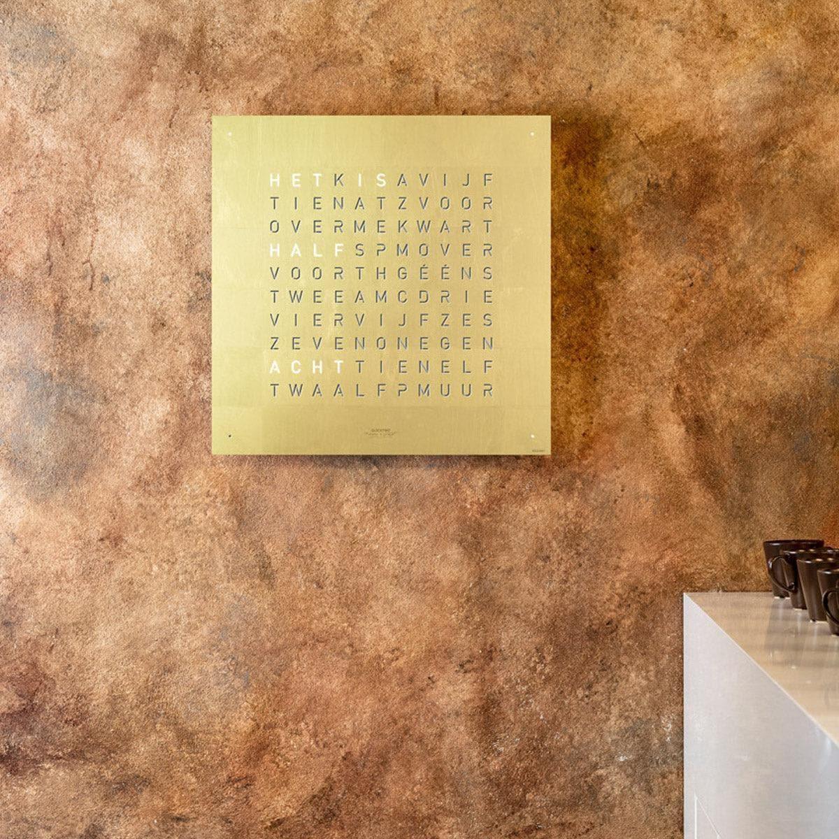 QLOCKTWO EARTH 45 Gold – vooraanzicht van de luxe wandklok met bladgouden afwerking, uit de exclusieve Creator’s Edition